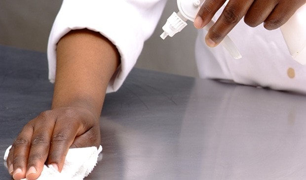 Hand with cloth wiping counter.