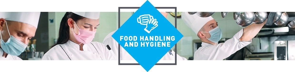 Chefs in kitchen wearing hats, jackets and masks. 