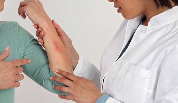 Doctor looking at scrape on arm. 