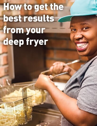Smiling woman operating deep fryer.