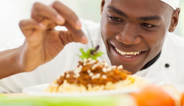 Chef garnishing dish.
